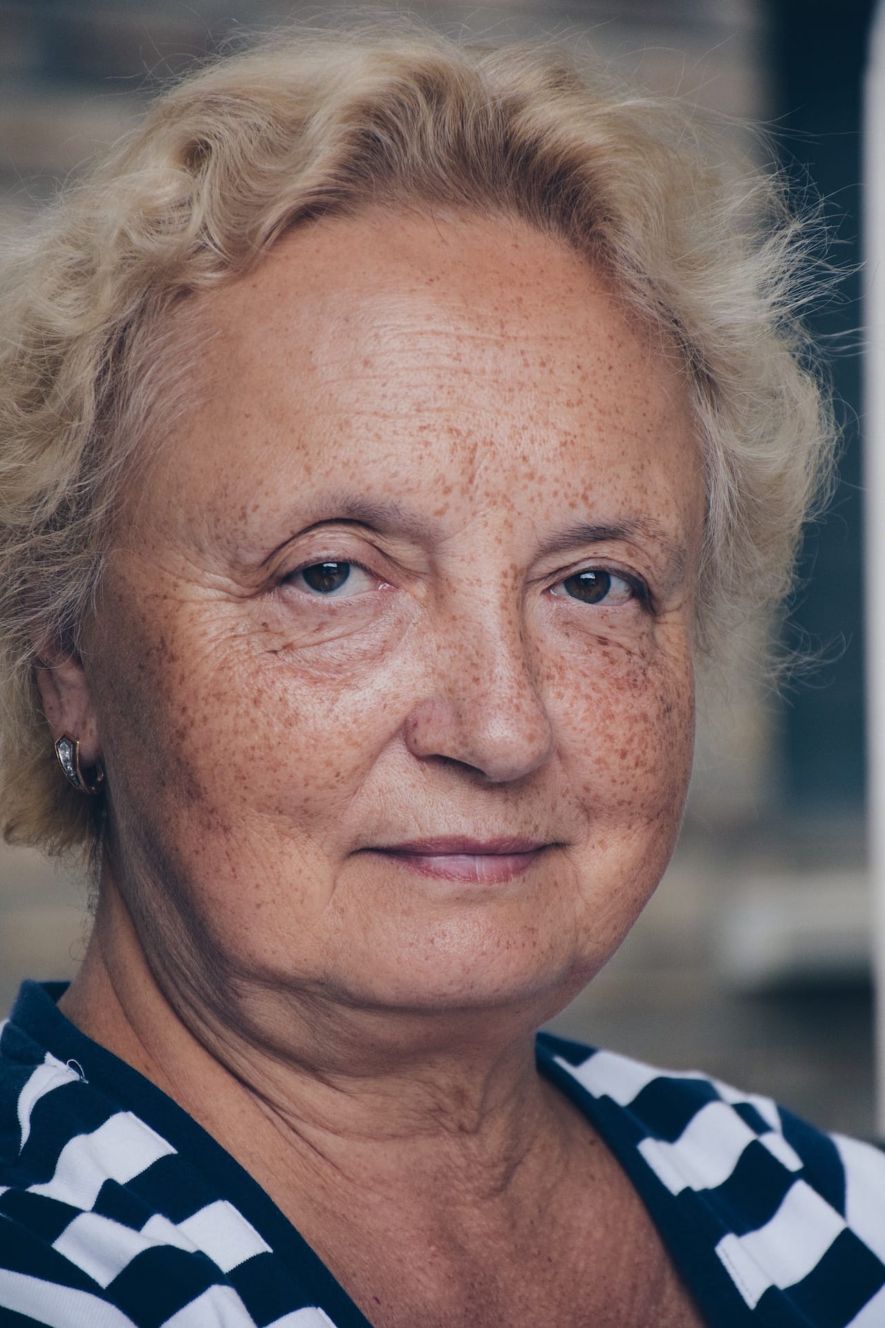 A portrait of a beautiful older woman with freckles on her face, looking into the camera smiling